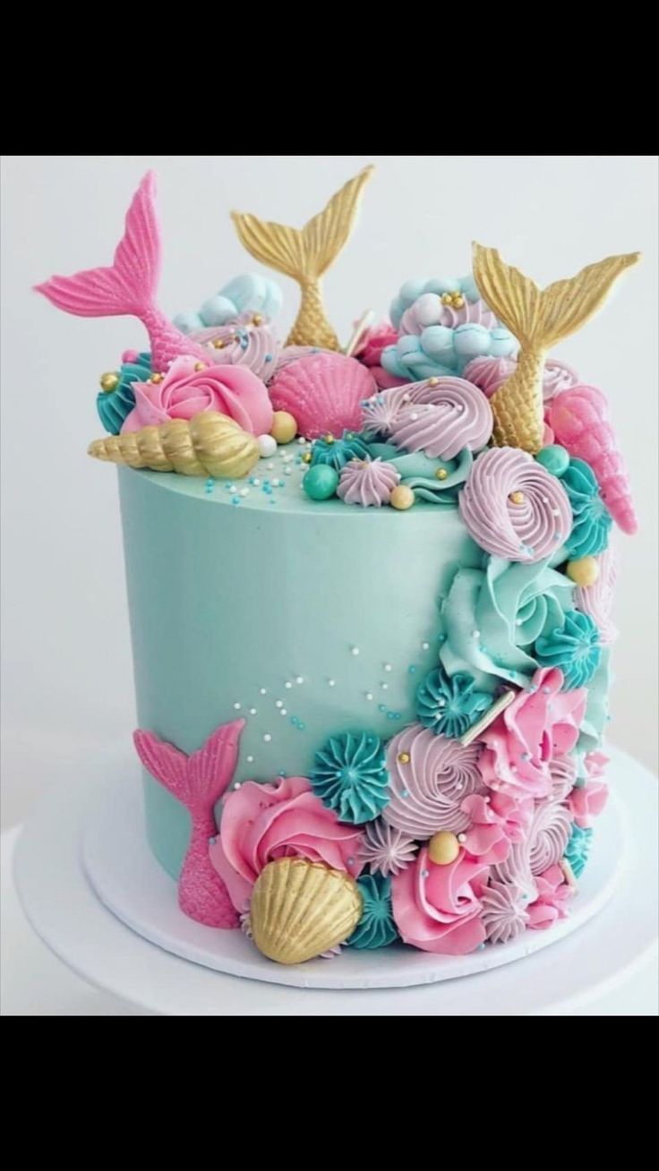 a blue and pink cake decorated with sea shells, seashells and mermaid tails