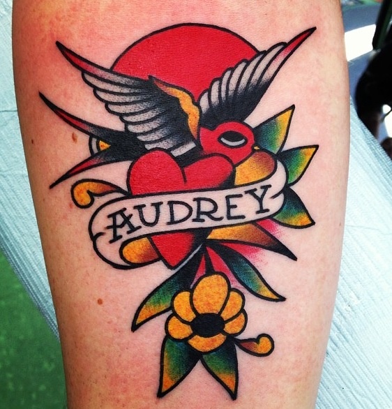 a tattoo on the leg of a person with a bird and banner above it that says audrey