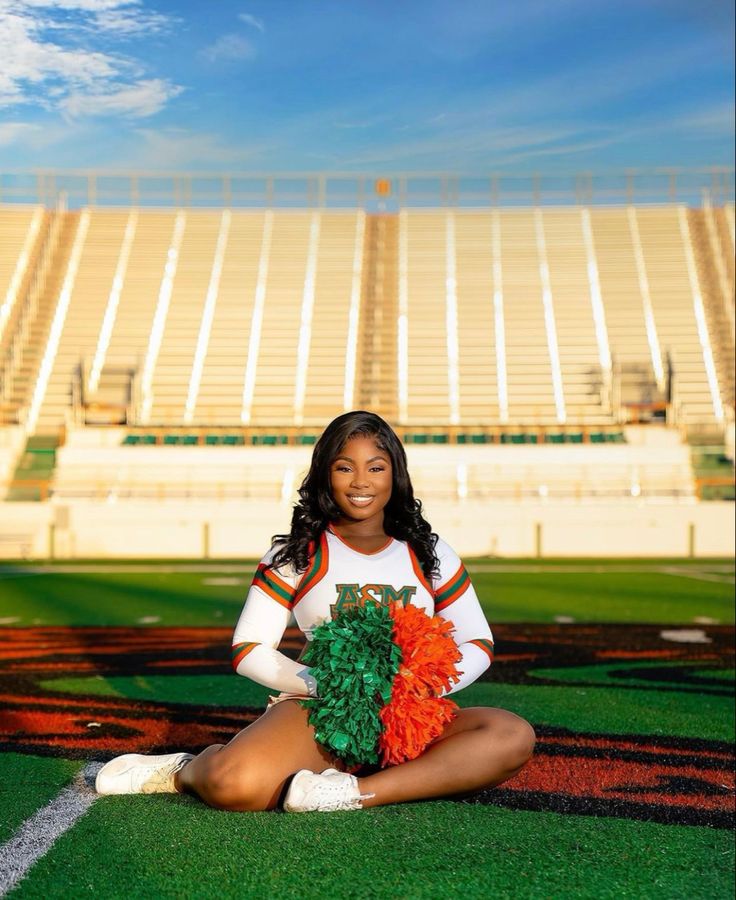 a cheerleader sitting on the ground with her pom poms in front of an empty stadium