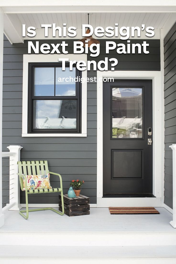 the front door of a gray house with white trim and black shutters is flanked by a green bench