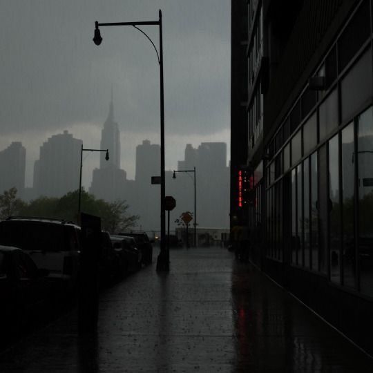 a dark city street with traffic lights and buildings in the background