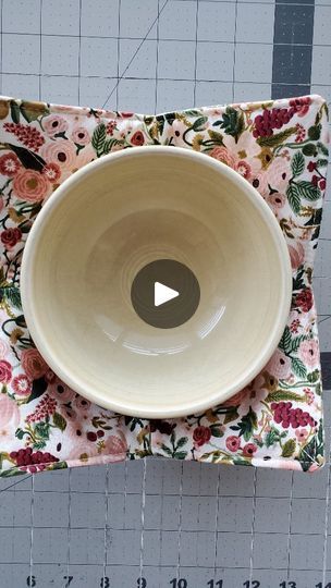 a white bowl sitting on top of a flowered cloth covered placemat with a hole in the center