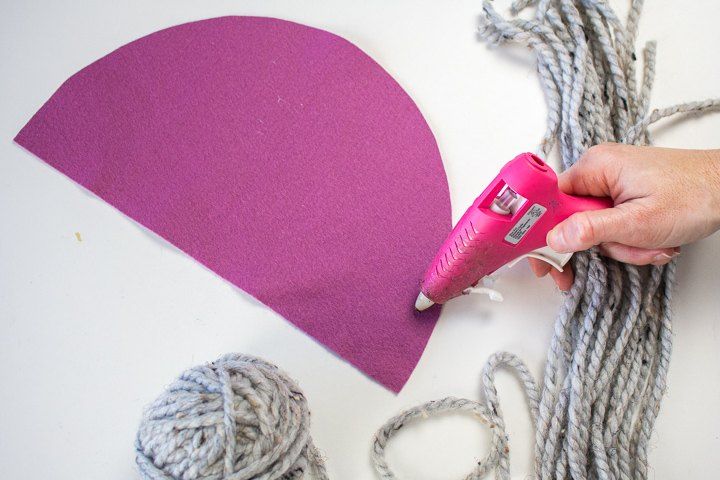 someone is making a heart shaped craft with yarn and glue on the table next to it