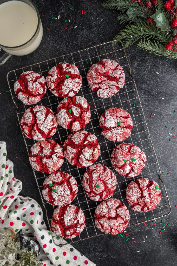 red velvet cookies on a cooling rack next to a glass of milk and christmas decorations