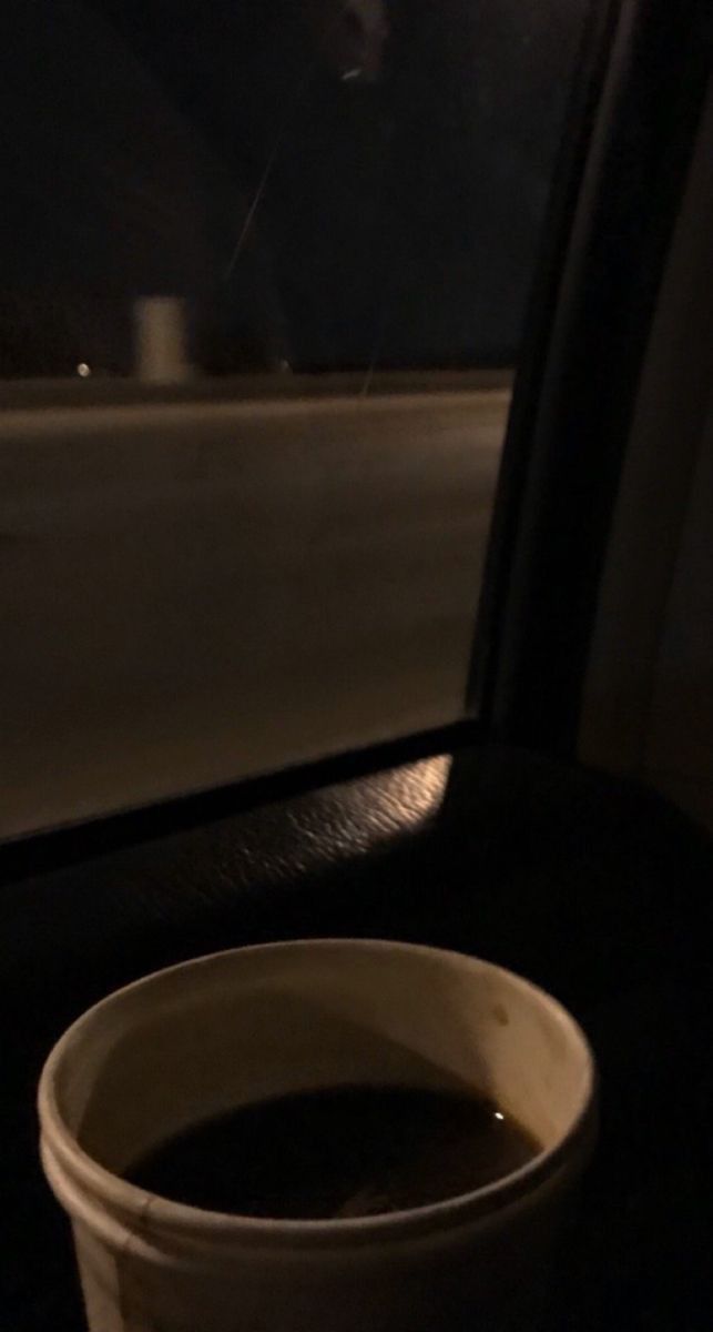 a cup of coffee sitting on top of a table next to a car door window