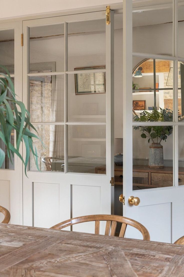 a wooden table sitting in front of a white door with glass panels on the doors