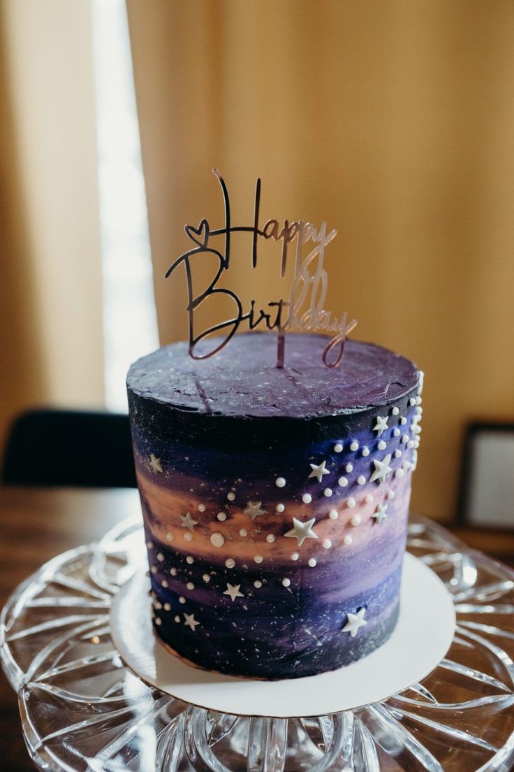 a birthday cake with stars on it sitting on a glass plate in front of a window