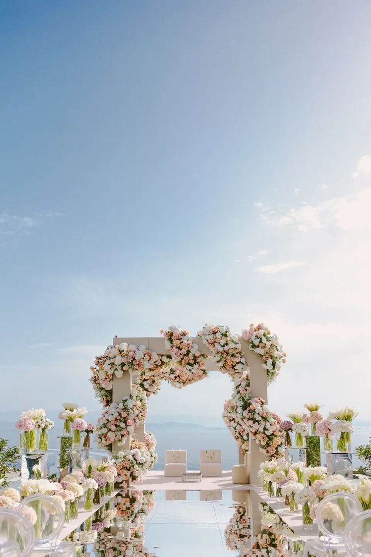 an outdoor ceremony setup with flowers and greenery on the aisle, overlooking the ocean