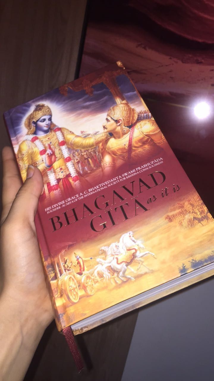 a hand holding up a book about bhagavati gita