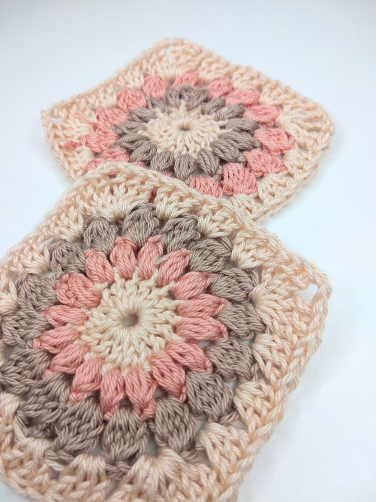 two crocheted coasters sitting on top of a white table next to each other