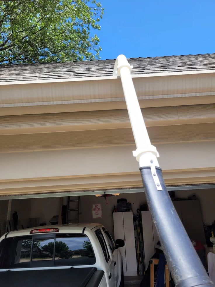 a car parked in front of a garage with a pole sticking out of it's roof