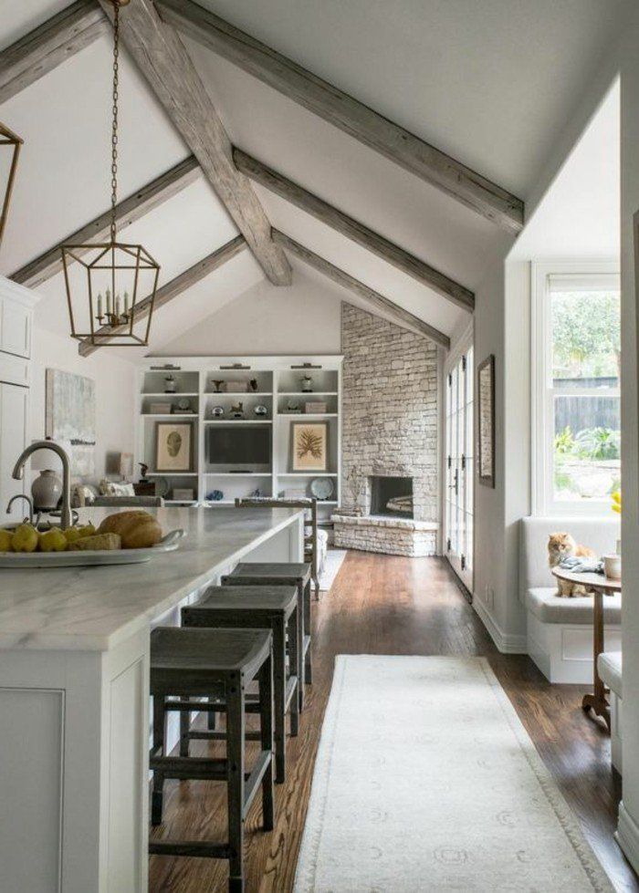 an open kitchen and dining room with exposed beams in the ceiling, along with wooden flooring