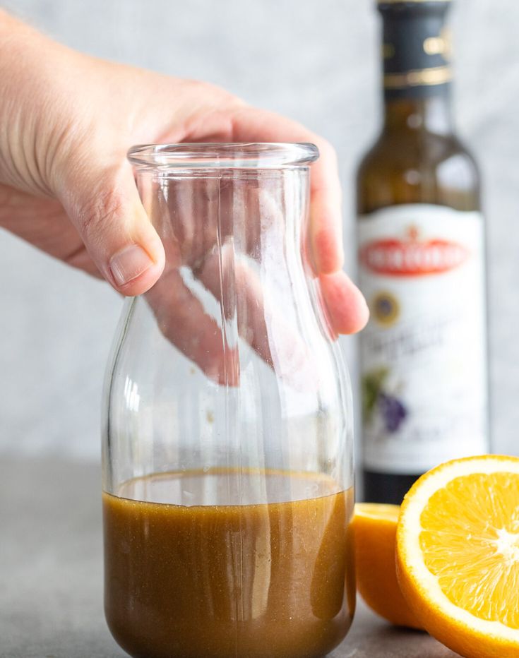 someone is adding orange juice to a drink in a glass pitcher next to an orange slice