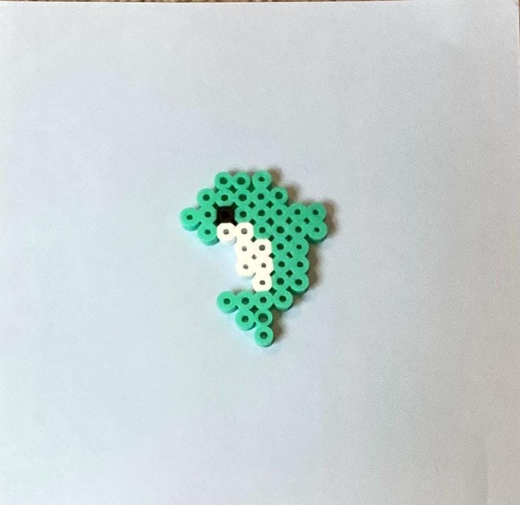 a green and white brooch sitting on top of a piece of paper