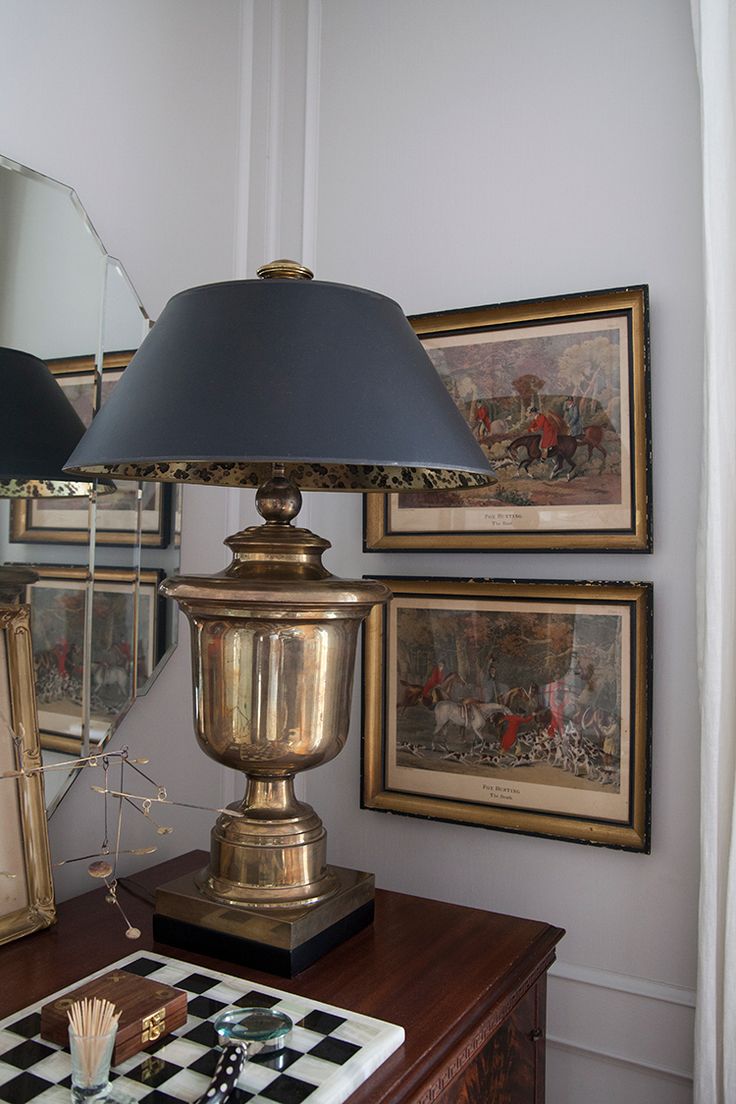 a lamp sitting on top of a wooden table next to a mirror and chess board