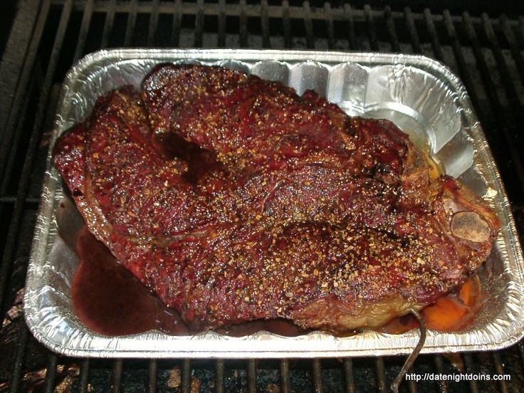 a piece of meat sitting on top of an open grill with sauce and seasoning