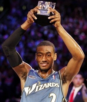 a basketball player holding up a trophy in front of his head and hands with both hands