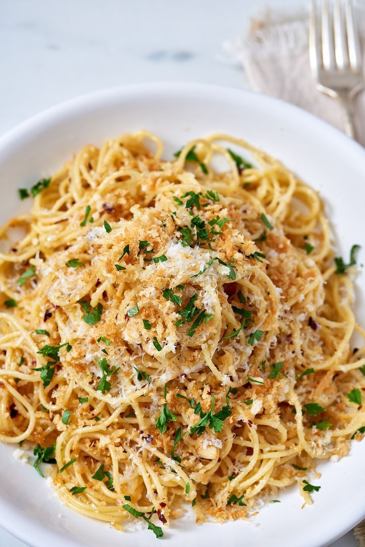 a white plate topped with spaghetti and parmesan cheese