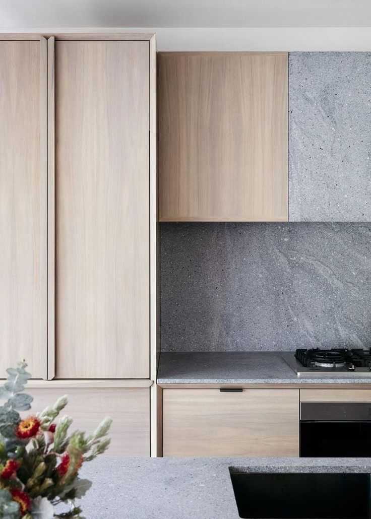 a kitchen with marble counter tops and cabinets next to a vase filled with flowers on the counter