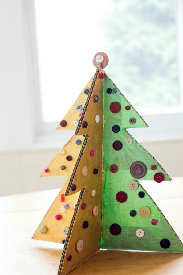 a small wooden christmas tree with buttons on it's sides, sitting on a table in front of a window