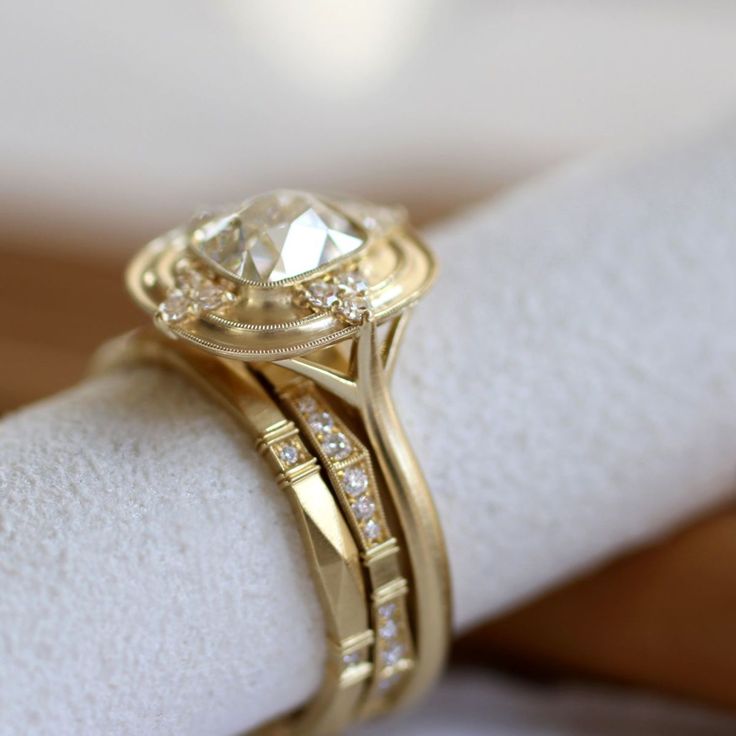 a close up view of a diamond ring on top of a white napkin with gold trim