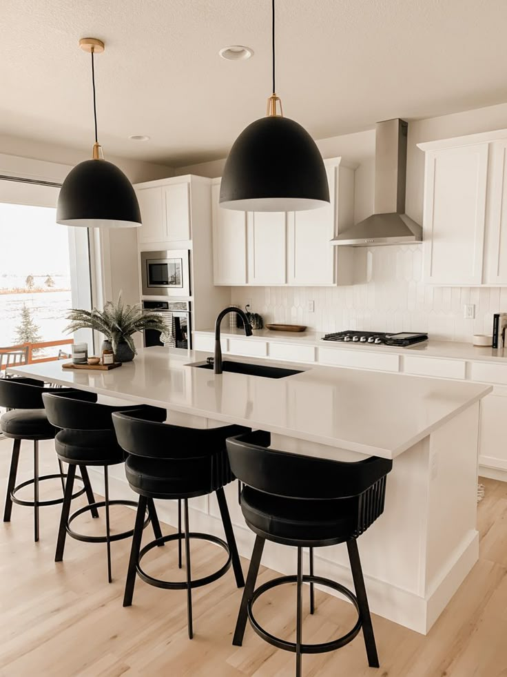 a kitchen with white counter tops and black bar stools next to an island in the middle