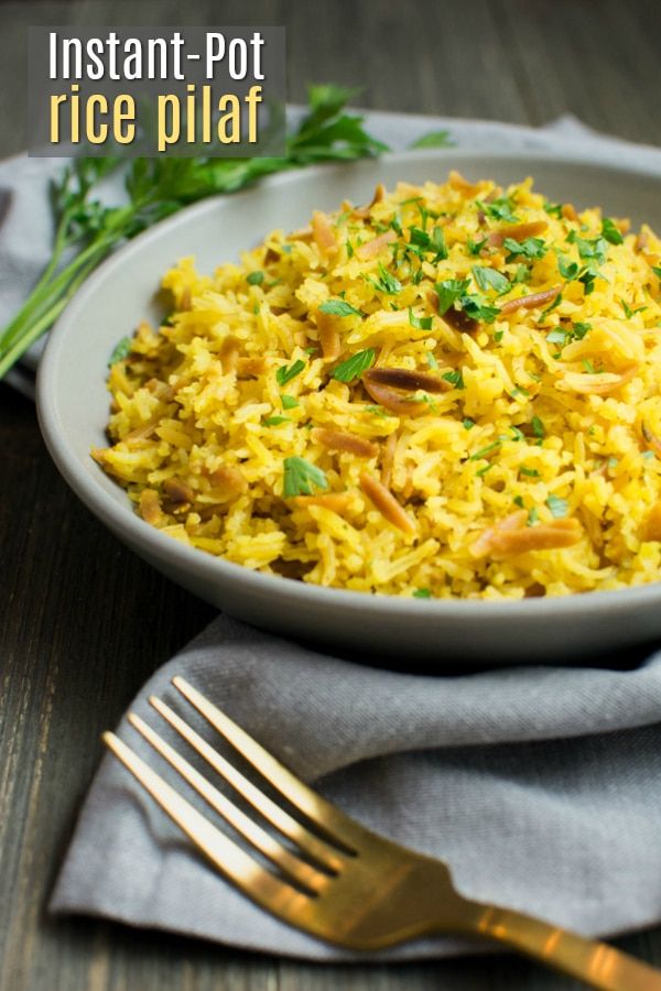 rice pilaf in a white bowl with gold fork and napkin on the side