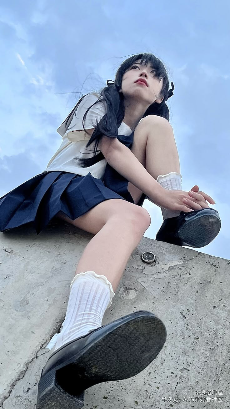 a woman sitting on top of a cement wall with her legs crossed and wearing knee high socks