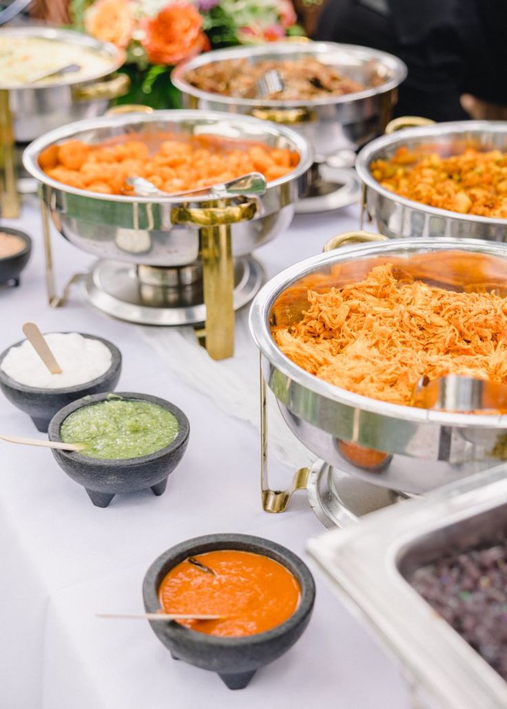 a buffet table filled with lots of different types of food and dipping sauces on it