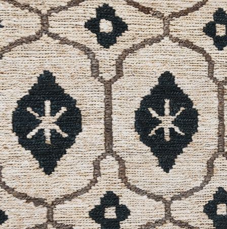 an area rug with black and white designs on the front, along with a beige background