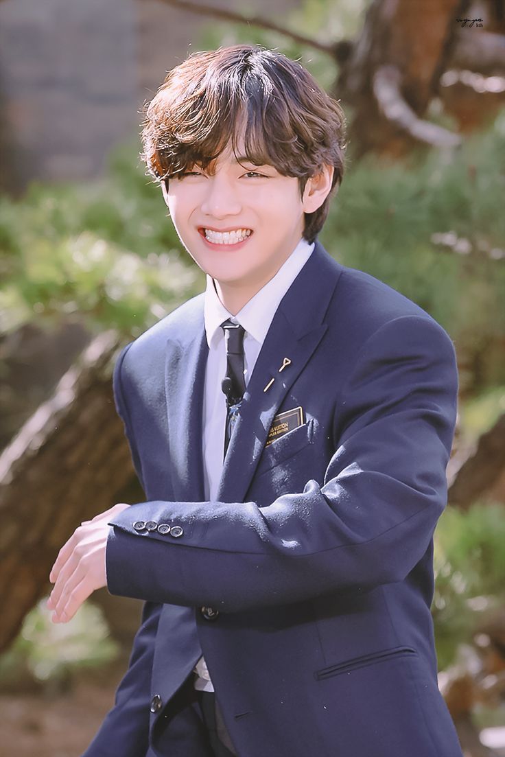 a young man in a suit and tie posing for a photo with his arms crossed