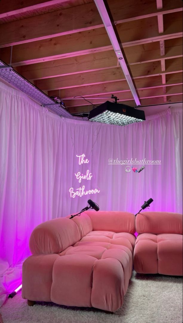 a pink couch sitting in front of a purple curtain