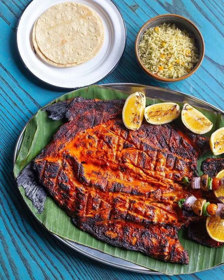 grilled fish on a platter with lemons and rice