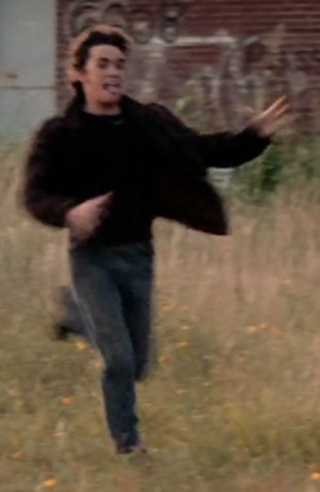 a man is running in the grass with his arms out to catch a frisbee