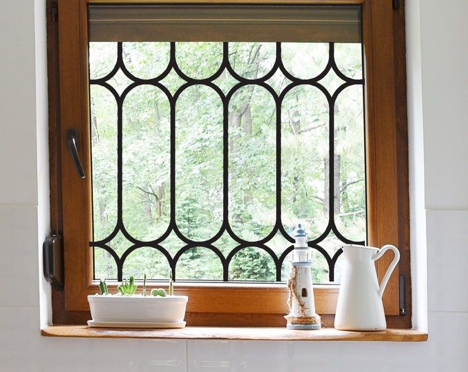 a kitchen window with potted plants in front of it and a watering can on the ledge