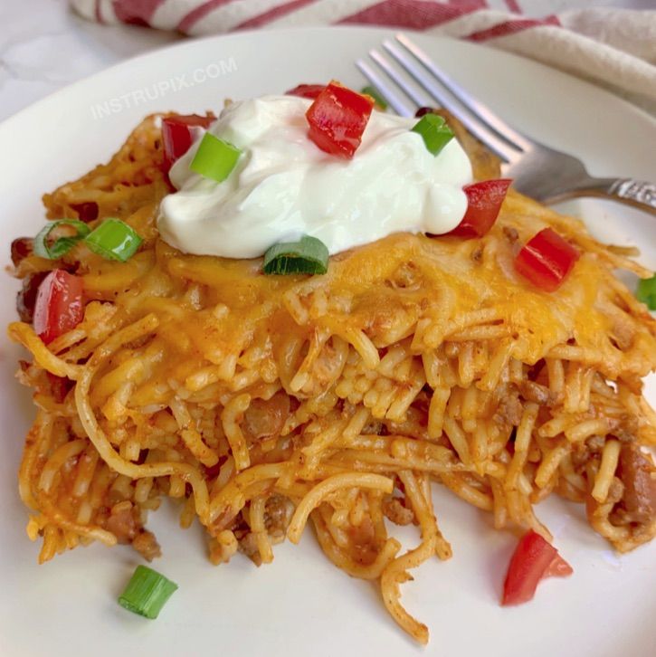 a close up of a plate of food with noodles and sour cream on top,