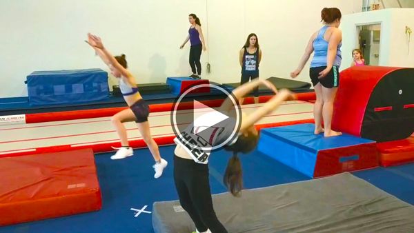 a group of women standing on top of a blue and red trampoline in a gym