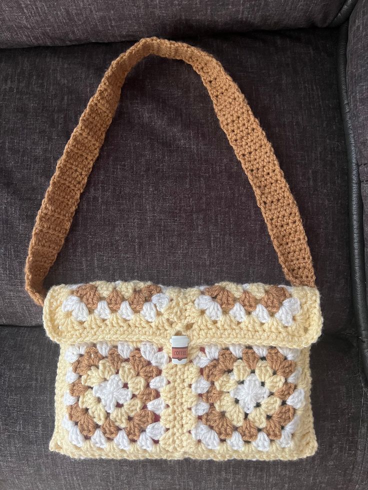 a crocheted purse sitting on top of a gray couch next to a pillow