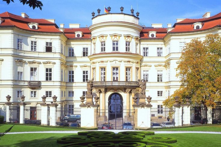 a large white building with many windows on the top floor and an orange roof above it