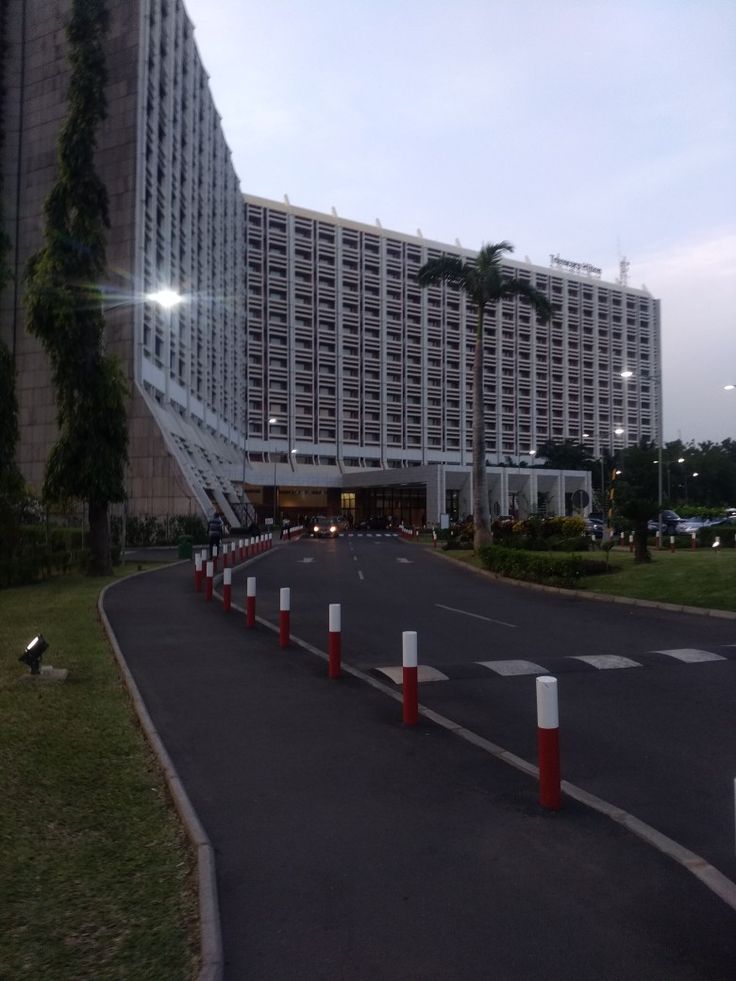 an empty street in front of a large building with palm trees on the side of it