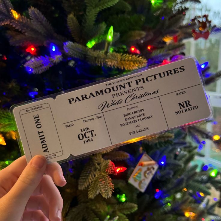 someone is holding up a ticket to see what's on the tree in front of them