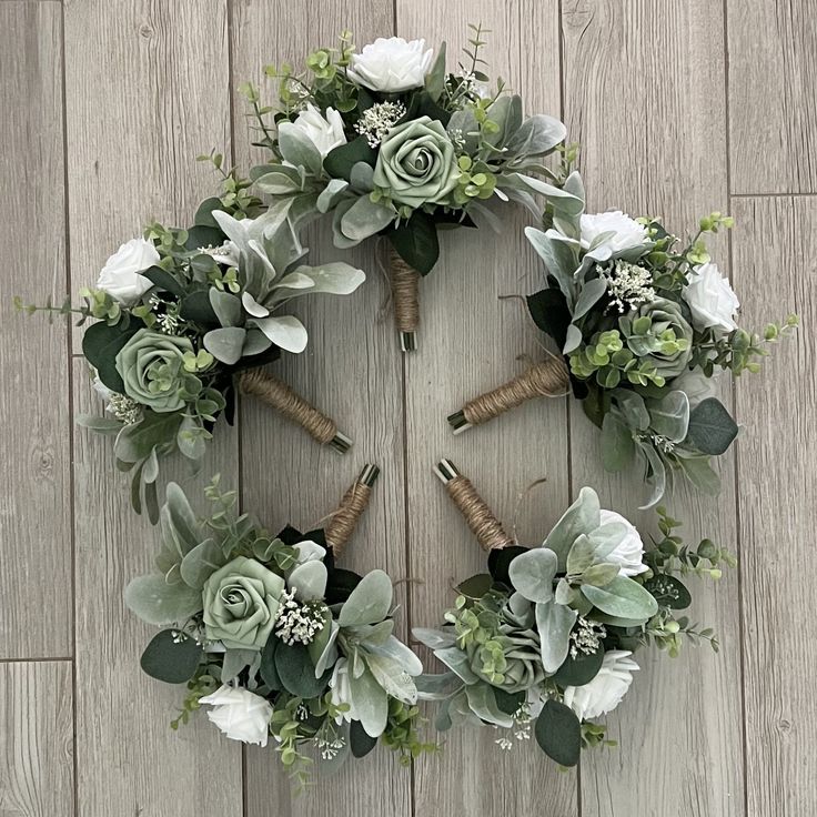 a wreath with white flowers and greenery on a wooden floor