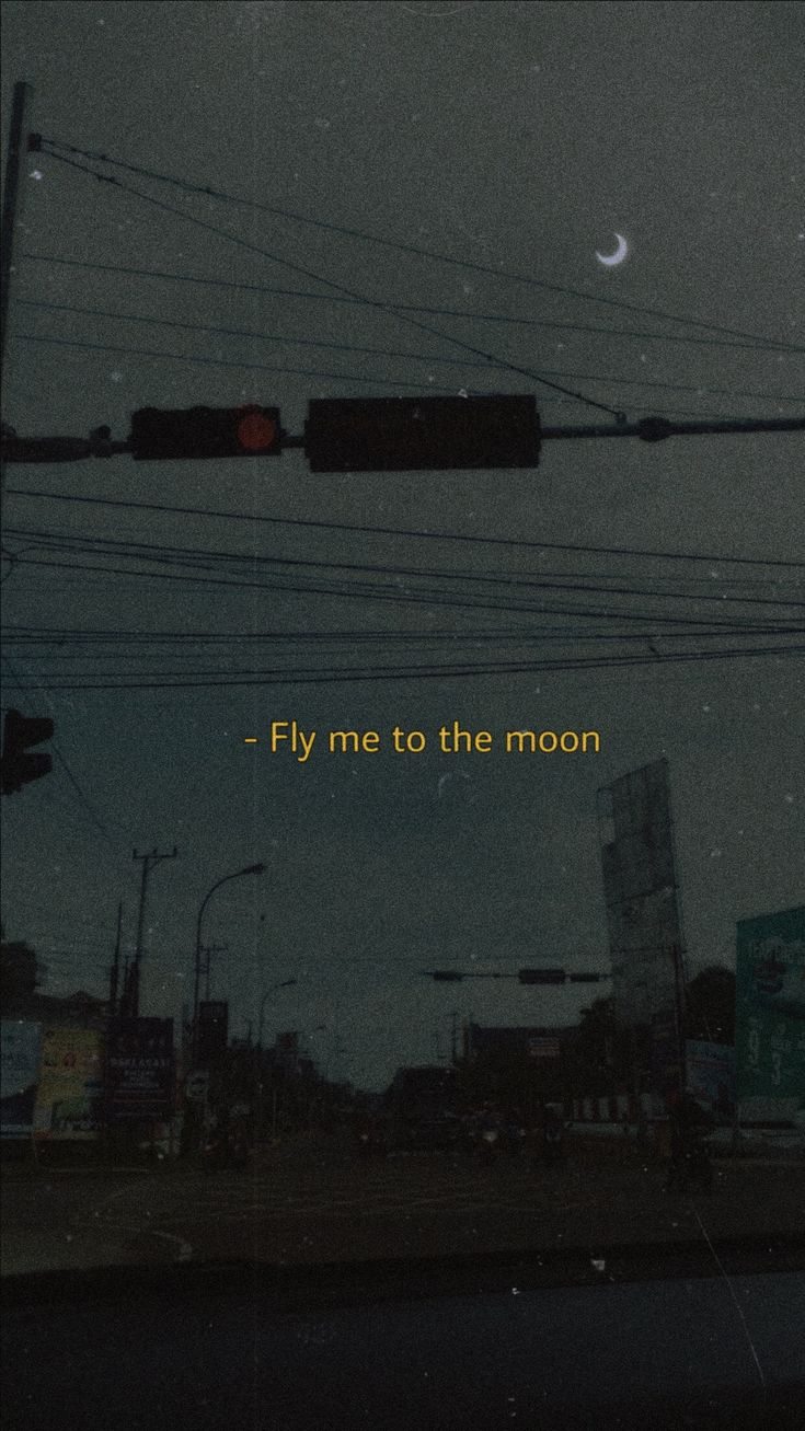 a traffic light with the words fly me to the moon written on it at night