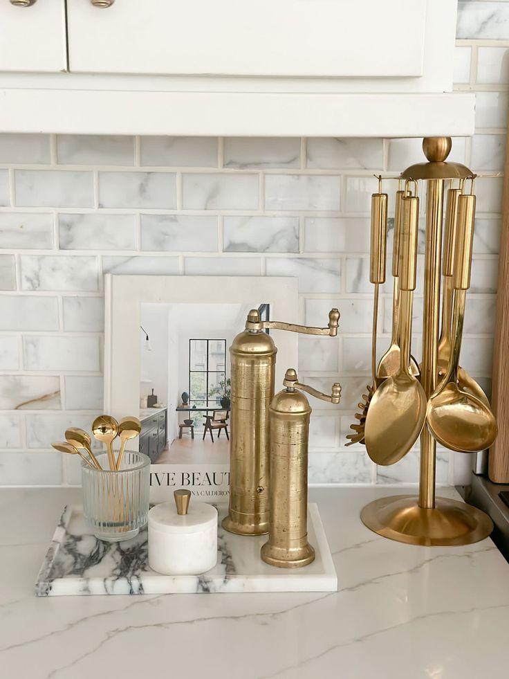 gold kitchen utensils are sitting on a marble countertop