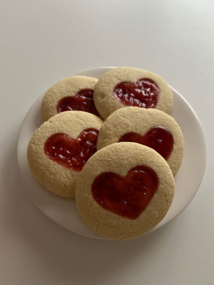 four heart shaped cookies on a plate with ketchup in the middle and another cookie next to it