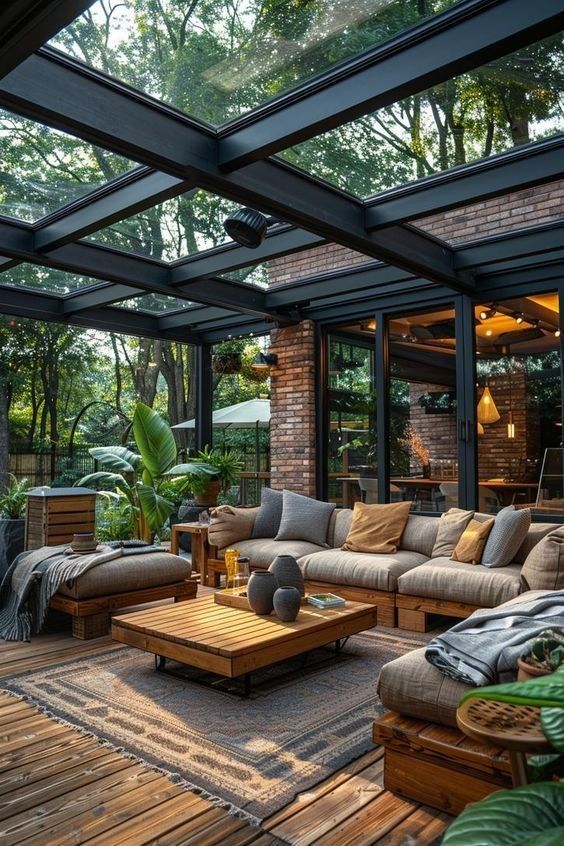 a living room filled with lots of furniture under a glass roof covered in greenery