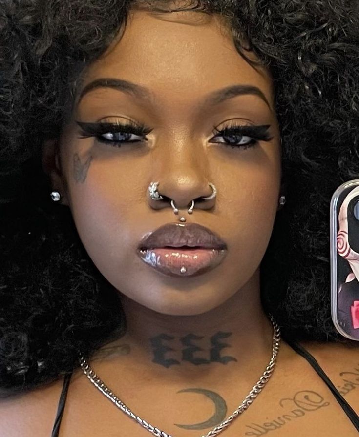 a woman with piercings on her nose holding a cell phone