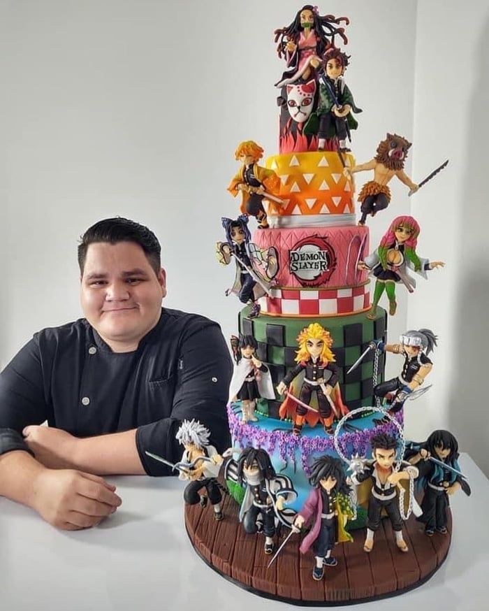 a man sitting in front of a giant cake with many figurines on it