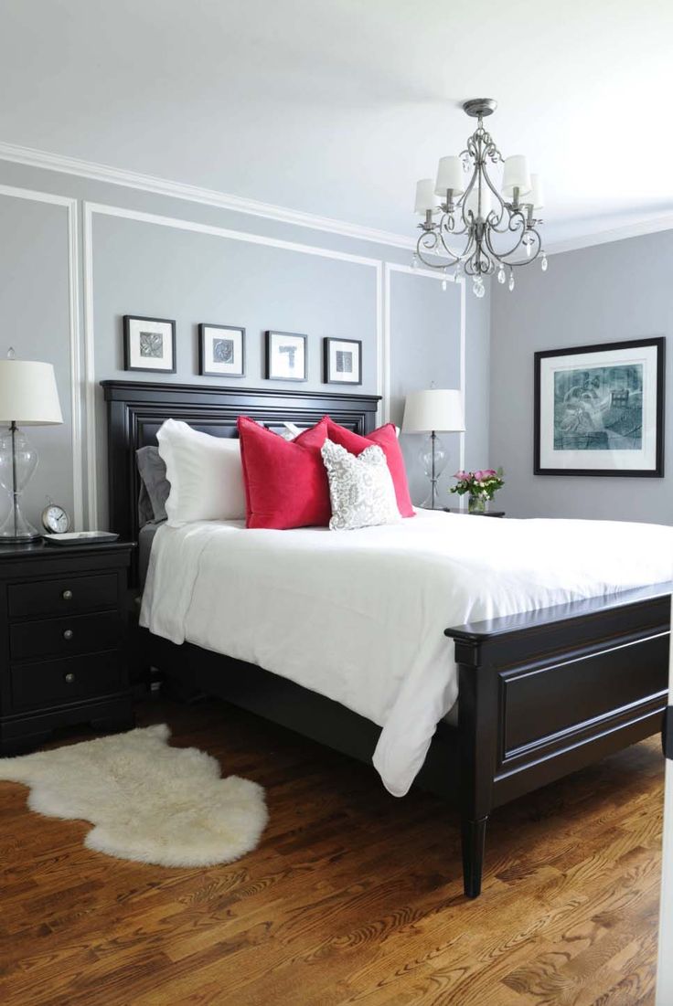 a bedroom with gray walls, white bedding and red pillows on the headboard