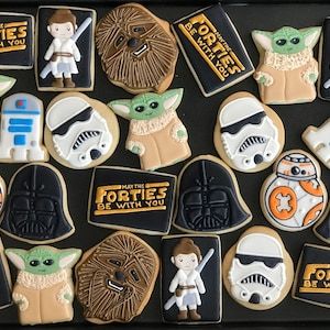 star wars cookies are arranged on a black tray with white frosting and brown icing